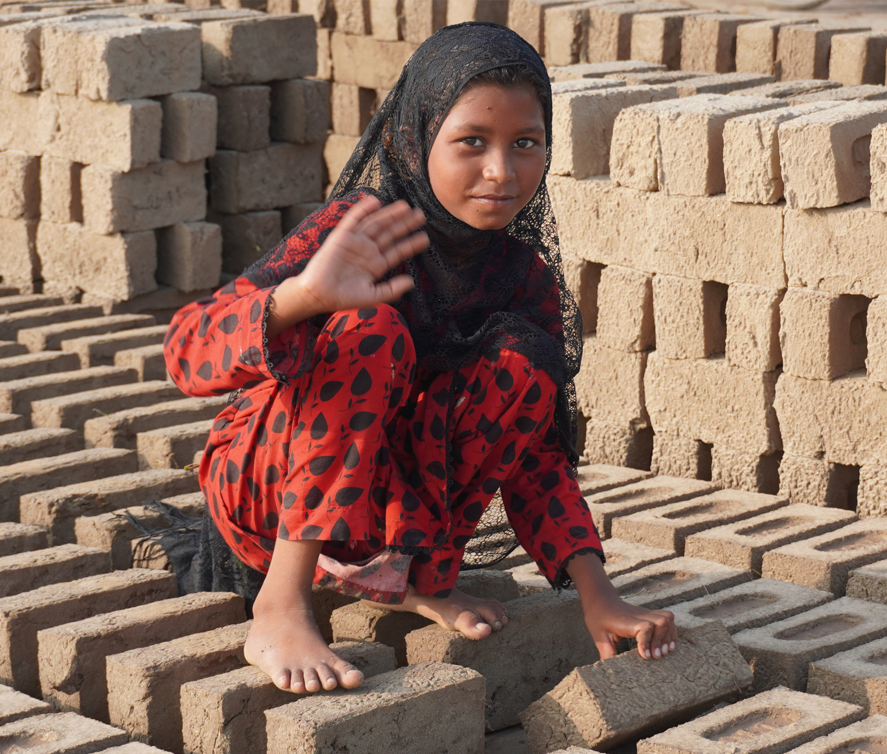 Young girl sitting among bricks in Pakistan